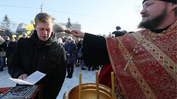 Ein Student wird von einem Geistlichen in Ivanovo gesegnet