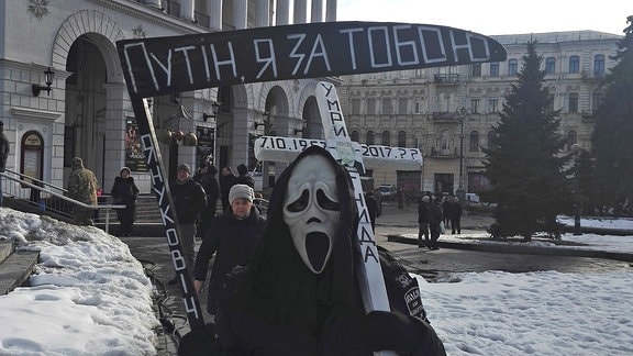 Ein Demonstrant als Sensenmann verkleidet, wünscht dem russischen Präsidenten Putin den Tod