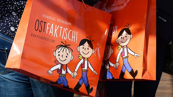 Orangefarbenen Papiertüten von der Eulenspiegel Verlagsgruppe mit den Zeichentrickfiguren Lolek und Bolek