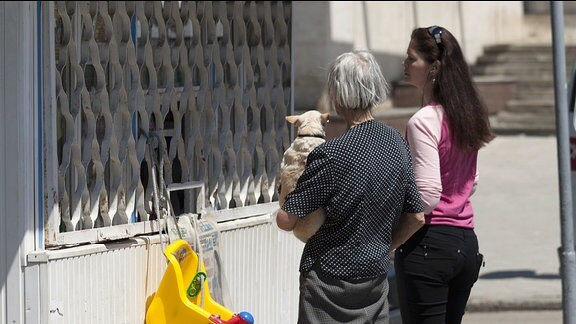 Zwei Frauen mit Hund auf dem Arm warten an einem Zeitungskiosk in Tiraspol.
