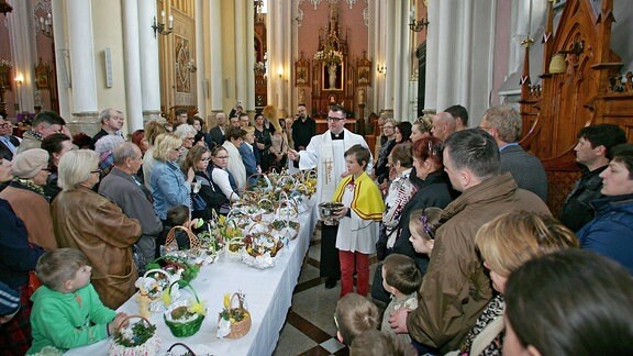 Ein Priester segnet Lebensmittel in einer Kirche am Karsamstag.
