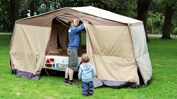 Ein Mann baut mit seiner Tochter einen Zeltanhänger Camptourist CT-7 in Leipzig auf.