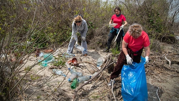 Drei Frauen beim Einsammeln von Müll.