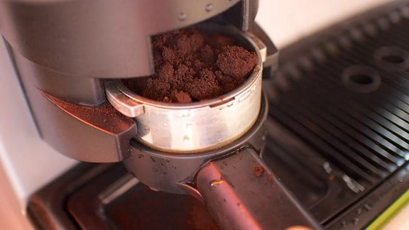Mit Kaffeepulver gefüllter Siebträger wird an einer Kaffeemaschine befestigt