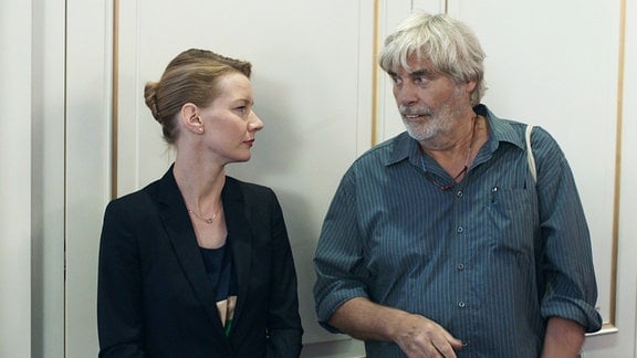 Sandra Hüller und Peter Simonischek, eine blonde Frau in dunkler Kleidung und ein grauhaariger Mann in einem Hemd