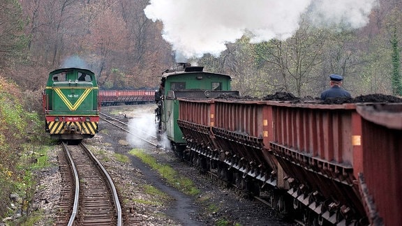 Zwei Damplokomotive der Baureihe 83 begegnen sich. Sie zieht Kohlewaggons.