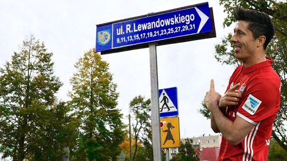 Robert Lewandowski zeigt auf Straßenschild (Bildmontage)