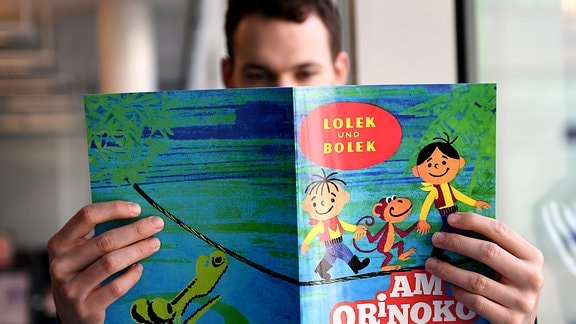 Ein Mann hält ein Heft von «Lolek und Bolek» in der Hand.