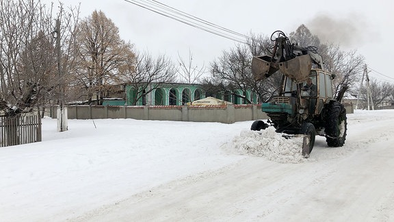 Eine verschneite Straße mit Bagger in Braviceni.