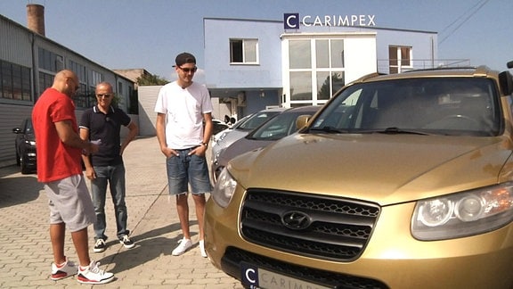 Die Rapper Gogo und Rytmus vor Autohaus mit Gold-lackiertem SUV der Marke Hyundai