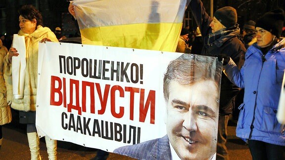 Ukraine, Kiew: Demonstranten halten während einer Versammlung vor dem Marienpalast ein Banner mit dem Bild von Saakaschwili, dem früheren georgischen Präsidenten und der Aufschrift "Poroschenko! Lass Saakaschwili gehen!" in den Händen.
