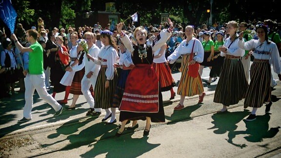 Frauen in estnischen Trachten tanzen und singen auf Straße