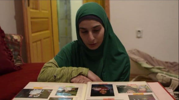 Eine Frau mit Kopftuch schaut sich ein Fotoalbum an