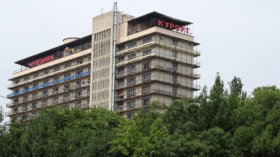 mehrstöckiges sowjetisches Hotel ragt hinter einem Waldstück hervor.