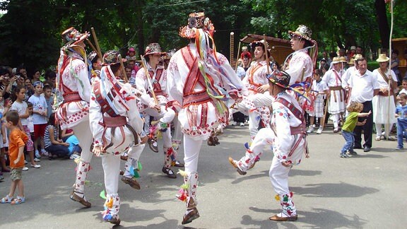 Männer in Trachten tanzen auf einem Fest.
