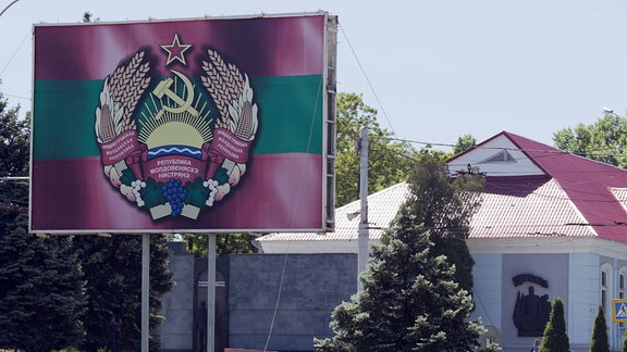 Staatswappen von Transnistrien mit Hammer und Sichel auf einem Aufsteller in Tiraspol.