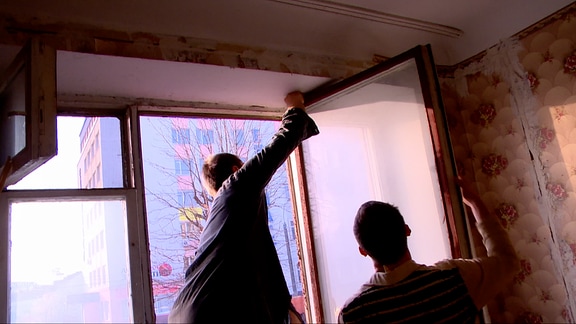 Zwei Männer reparieren alte Holzfenster 