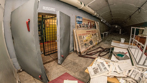 Ein Bunker aus Zeiten des Kalten Krieges mit Zeitungen und der Aufschrift „Ausgang“ über der Tür.