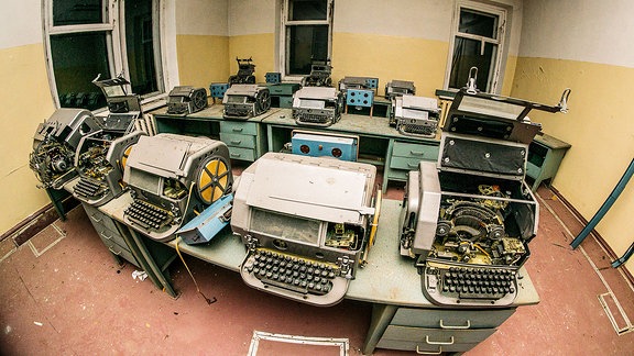 Schreibmaschinen aus Sowjetzeiten, die aufgereiht in einem verlassenen Büro stehen. 