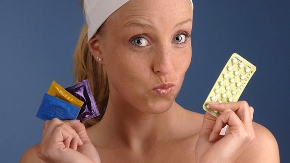 Eine junge Frau mit Kondomen und der Anti-Baby-Pille