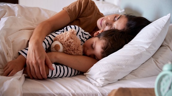 Eine Mutter kuschelt mit ihrem Kind im Bett