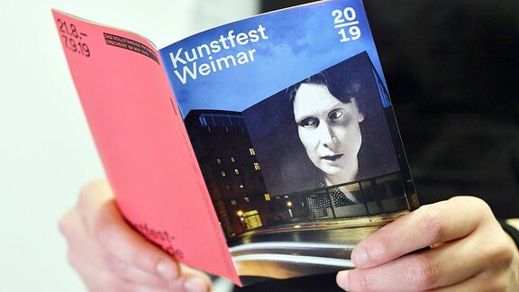 Eine Frau blättert im Programmheft für das Kunstfest Weimar 2019. 