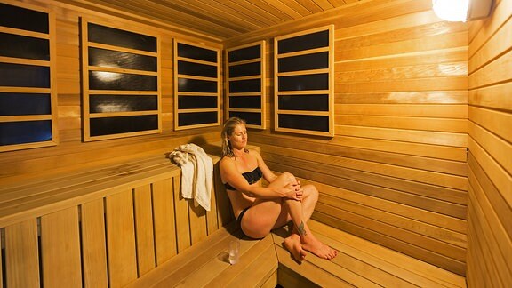 Eine Frau sitzt in einer Sauna