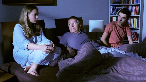 Lisa (Ella Zirzow, li.) und Jonas (Anthony Petrifke, re.) können nicht schlafen. Sie schleichen in Rolands (Thomas Rühmann, mi.) Schlafzimmer, auch er sollte jetzt nicht alleine sein.