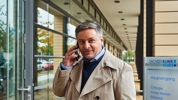 Joachim Bindel (Rüdiger Klink) telefoniert vor der Sachsenklinik