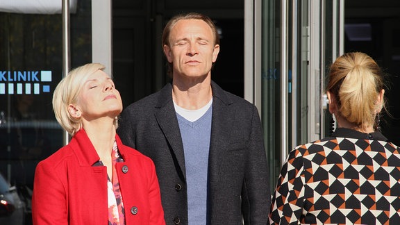 Zwei Schauspieler schließen die Augen, legen die Köpfe in den Nacken und lassen ihre Gesichter von der Sonne bescheinen.