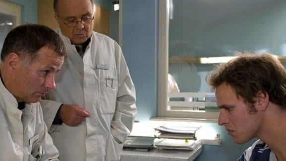 Dr. Heilmann und Prof. Simoni untersuchen Renés verwundeten Daumen.