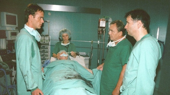Prof. Simoni (Dieter Bellmann, 2.v.r.), Roland Heilmann (Thomas Rühmann, r.) und Achim Kreutzer (Holger Daemgen) sind betroffen.