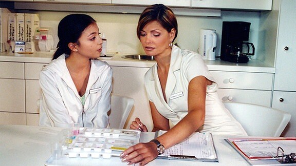 Schwester Yvonne (Maren Gilzer) erklärt Arzu (Arzu Bazman) an ihrem ersten Klinikarbeitstag, wie die Tabletten zu sortieren sind.