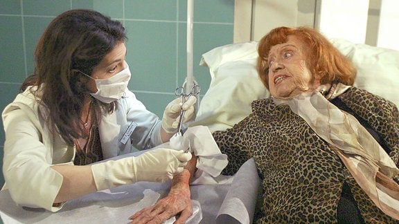 Dr. Elena Eichhorn (Cheryl Shepard) versorgt die Verbrennungswunden von Maria Herrmann (Brigitte Mira).