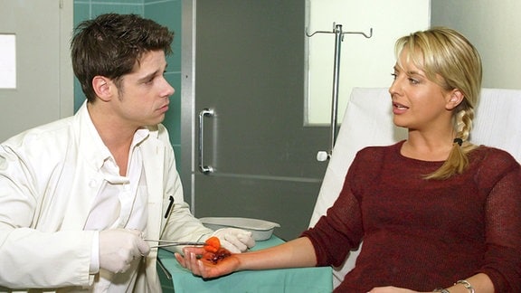 Vladi (Stephen Dürr), der seine Famulatur an der Sachsenklinik begonnen hat, versorgt Nicoles (Katrin Weißer) schmerzende Hand.