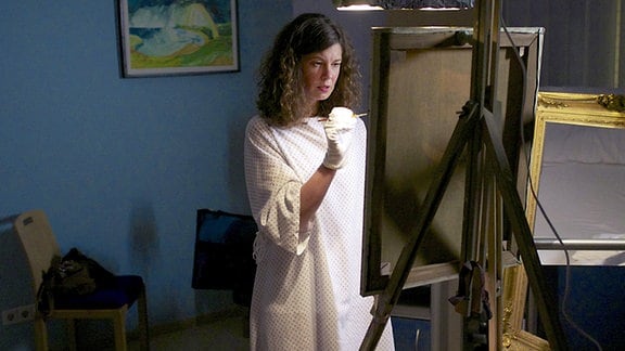 Iris Markgraf will in der Klinik ein Gemälde  fertigstellen. Kurze Zeit später bricht sie unter starken Schmerzen zusammen.