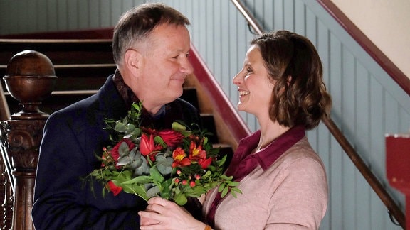 Roland (Thomas Rühmann) besucht Katja (Julia Jäger) mit einem Blumenstrauß.