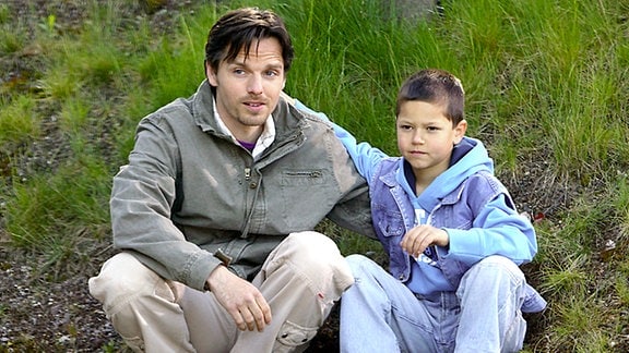 Peer Zarenthin sitzt mit seinem Sohn Tobias Winkler auf einer Wiese.