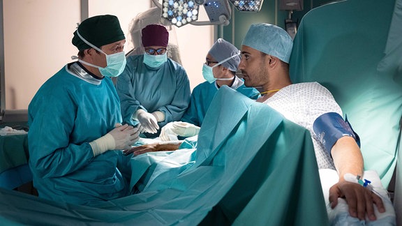 Tatsächlich hat sich Dr. Ilay Demir (Tan Caglar, re.) seine Hand so sehr verletzt, dass Dr. Philipp Brentano (Thomas Koch, li.) ihn operieren muss. 