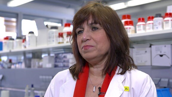 Eine Frau in einem weißen Kittel steht in einem Labor.