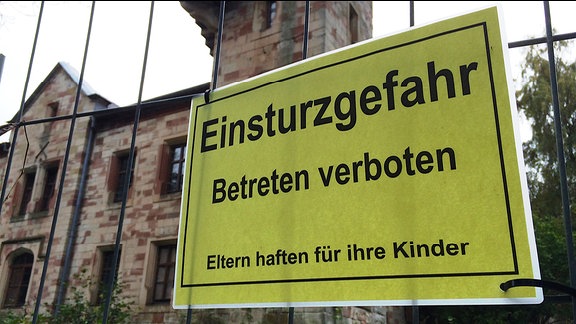 Ein Schild mit der Aufschrift "Einsturzgefahr Betreten verboten" an einem Bauzaun