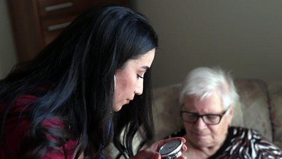 Auszubildende misst Blutdruck einer Seniorin