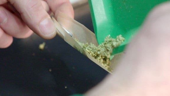 Cannabis wird auf einem Zigarettenpapier verteilt.