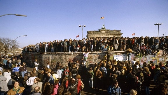 Menschen aus Ost und West feiern den Fall der Berliner Mauer vor dem Brandenburger Tor in Berlin