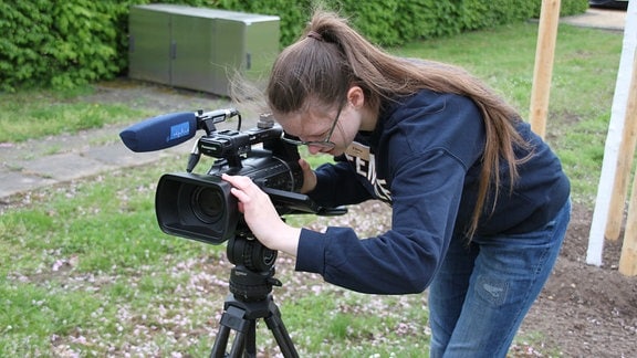 Ein Mädchen beugt sich über eine Videokamera