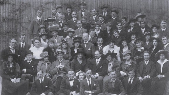 Schwarz-Weiß-Foto des Dirigenten Alfred Szendrei mit Ensemblemitgliedern der Wiener Volksoper 