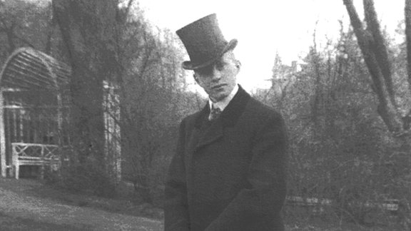 Schwarz-Weiß-Foto des Dirigenten Hans Weisbach als junger Mann auf dem Gartengelände seiner Eltern