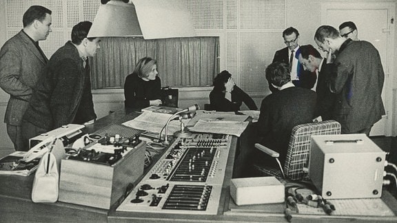 Schwarz-Weiß-Foto des Dirigenten Horst Neumann im Tonstudio mit Mitgliedern des Orchesters und der Tontechnik.