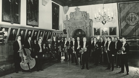 Schwarz-Weiß-Foto des Dirigenten Horst Neumann mit dem Rundfunk-Kammerorchester Leipzig im Festsaal des Leipziger Alten Rathauses.