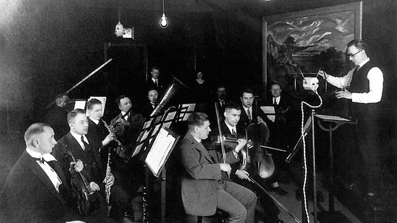 Schwarz-Weiß-Foto des Dirigenten Dr. med. Reinhold Merten mit der Hauskapelle des Radio Frankfurt. 